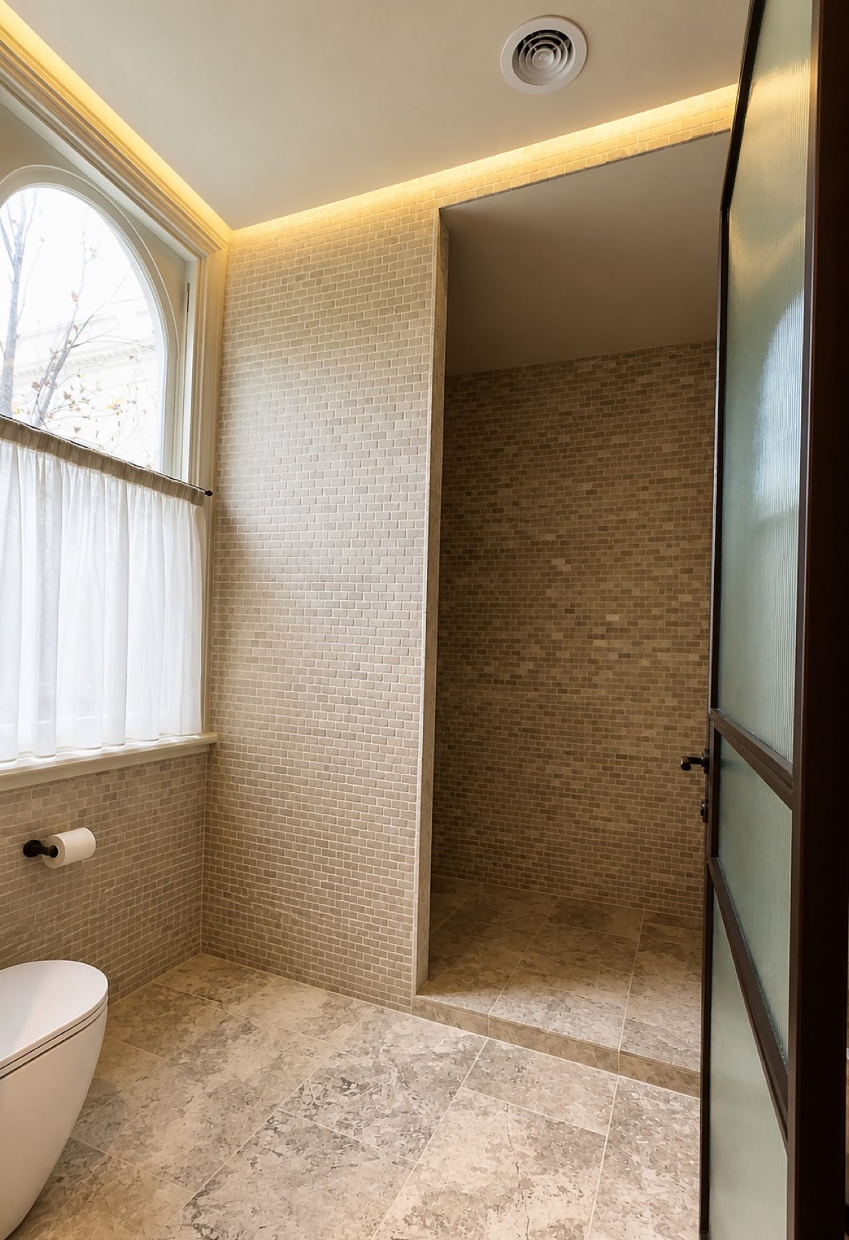 Completed curved stone mosaic bathroom with warm concealed lighting